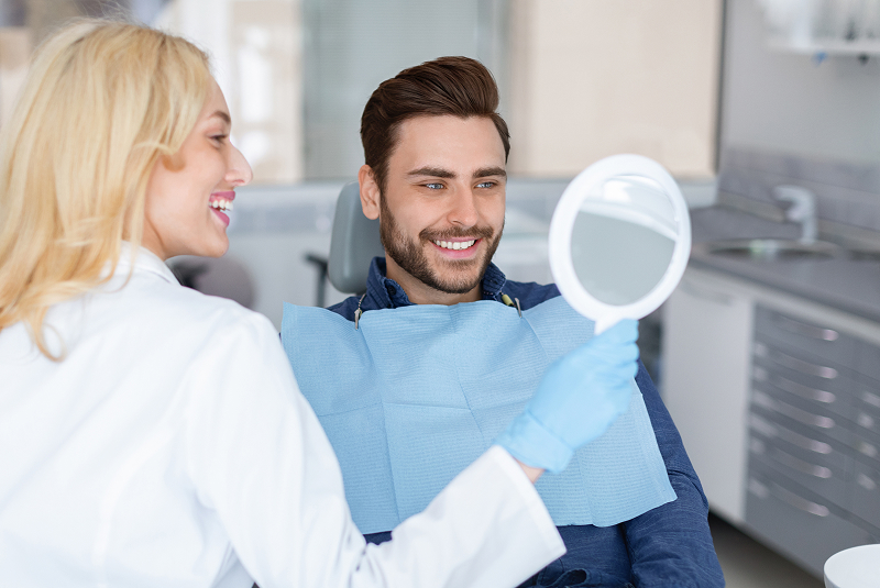Patient evaluating cosmetic dentistry results in mirror