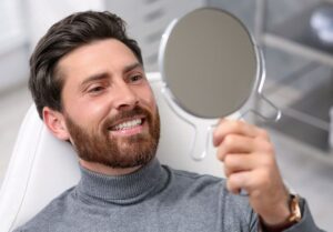 Guy in dental chair smiling looking into a mirror
