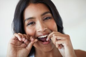 Woman flossing her teeth and smiling.